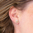 Load image into Gallery viewer, Silver stud earrings featuring found beach pebble, in model's right ear with hair swept back