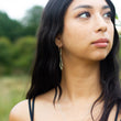 Load image into Gallery viewer, Handmade silver earrings in Dancing Kite design from the Windblown Collection, shown on headshot of model with greenery behind