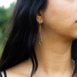 Load image into Gallery viewer, Side shot of handmade silver earrings in Dancing Kite design, in model's ear with her dark hair falling to the side