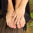 Load image into Gallery viewer, Close up shot of models hand and feet wearing the Tailwind anklet and delicate Tailwind charm bracelet