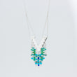 Load image into Gallery viewer, Close up of Windcharm handmade silver pendant necklace showing chain threaded through tube and green, blue and clear beads falling below