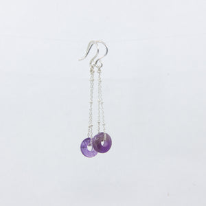 Purple gemstone and silver chain earrings on white background