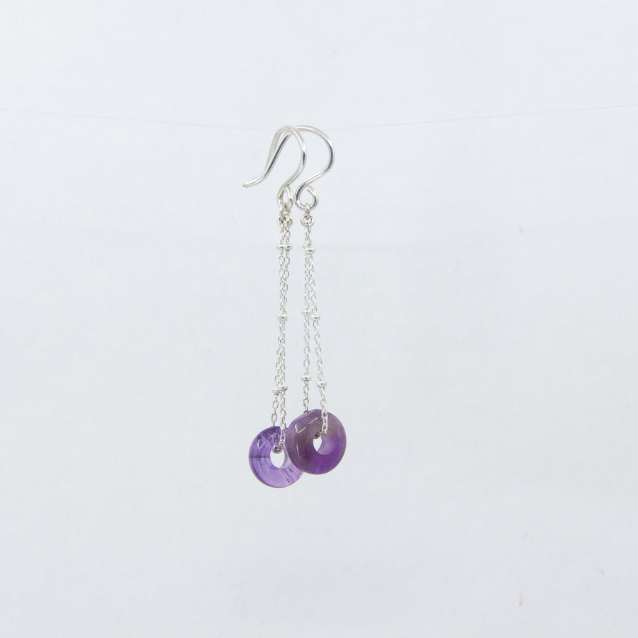 Purple gemstone and silver chain earrings on white background