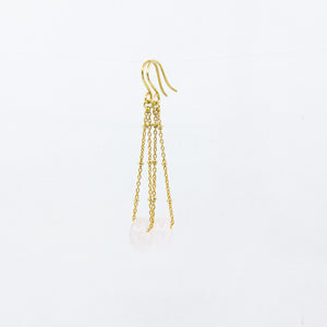 Pink gemstone and gold-plated chain earrings on white background