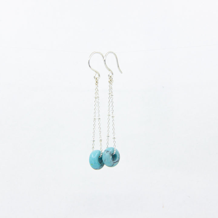 Turquoise gemstone earrings on silver satellite chain, against a white background