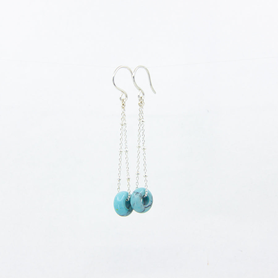 Turquoise gemstone earrings on silver satellite chain, against a white background