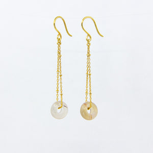 Translucent gemstone and gold-plated chain earrings on white background