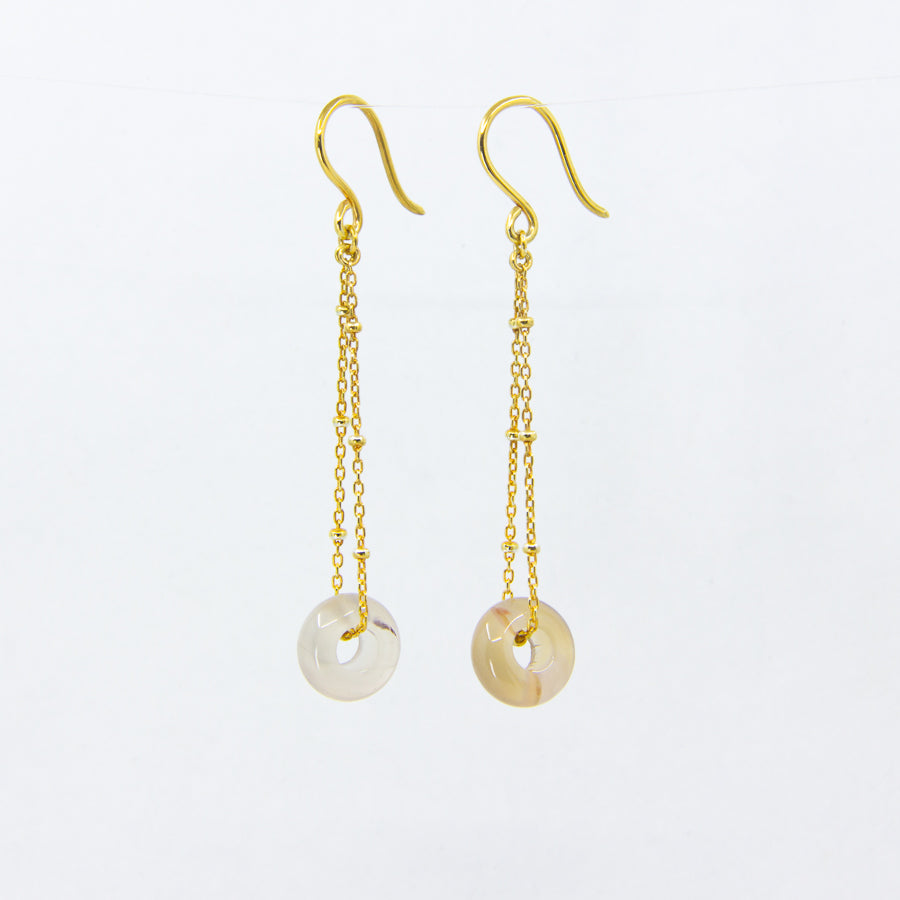 Translucent gemstone and gold-plated chain earrings on white background