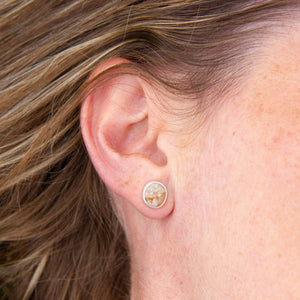 Silver stud earrings featuring found beach pebble, in model's right ear with hair swept back