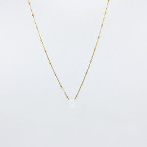 Clear gemstone and gold-plated necklace on white background