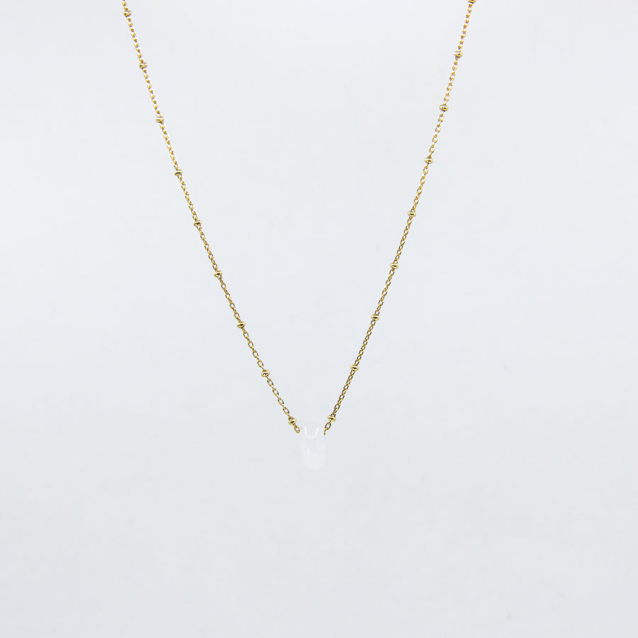 Clear gemstone and gold-plated necklace on white background