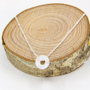 Circle gemstone pendant necklace with silver chain through on a circular wooden block