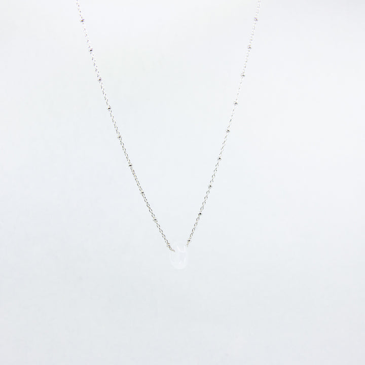 Silver necklace with a clear quartz gemstone pendant on white background