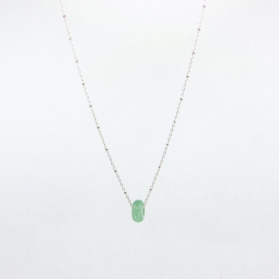 Green gemstone and silver chain necklace on white background