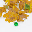 Load image into Gallery viewer, Circle gemstone pendant necklace with gold-plated chain through on a yellow oak leaf
