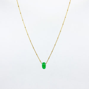 Deep green gemstone and gold-plated chain necklace on white background
