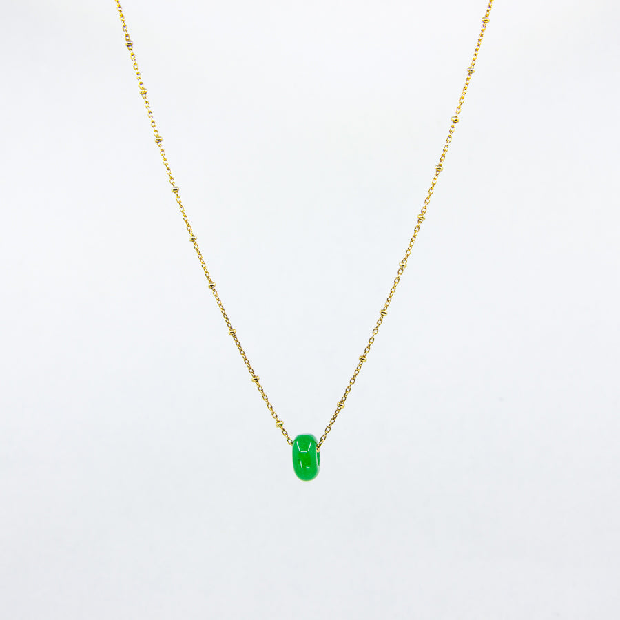 Deep green gemstone and gold-plated chain necklace on white background