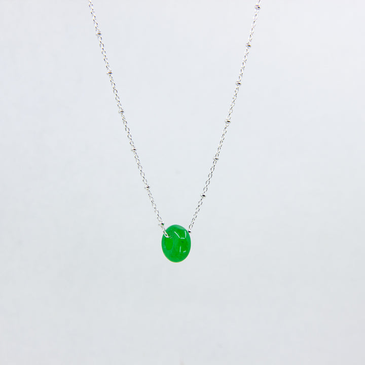 Silver necklace with jade gemstone on white background