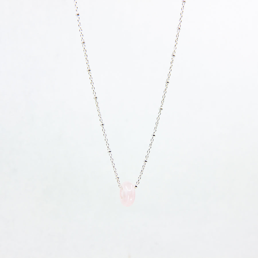 Pink gemstone and sterling silver necklace on white background