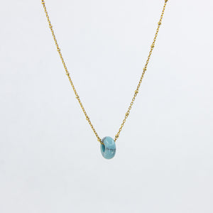 Circle gemstone pendant necklace with gold-plated satellite chain through, close up