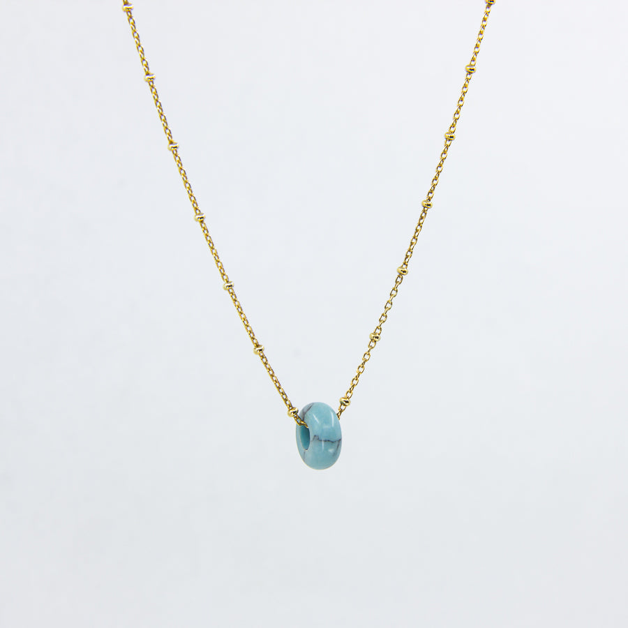 Circle gemstone pendant necklace with gold-plated satellite chain through, close up