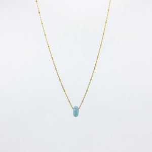 Turquoise gemstone and gold-plated necklace on white background