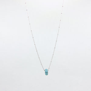 Silver necklace with a turquoise gemstone pendant on a white background