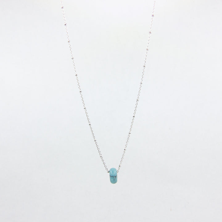Silver necklace with a turquoise gemstone pendant on a white background