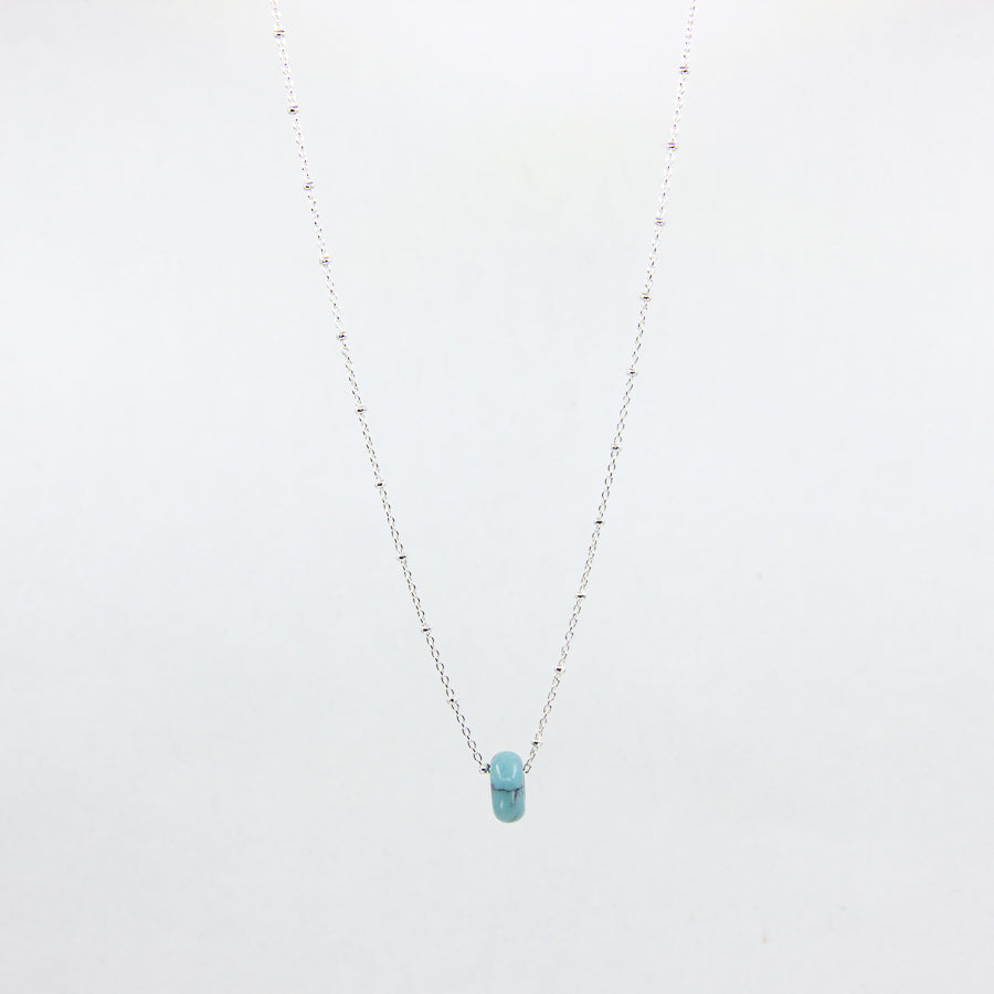 Silver necklace with a turquoise gemstone pendant on a white background