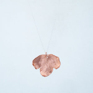 Front view of three segmented leaf necklace, dangling from chain on plain white background
