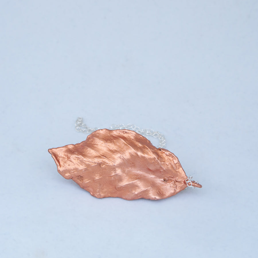 Back view of waving leaf with silver chain behind on white background