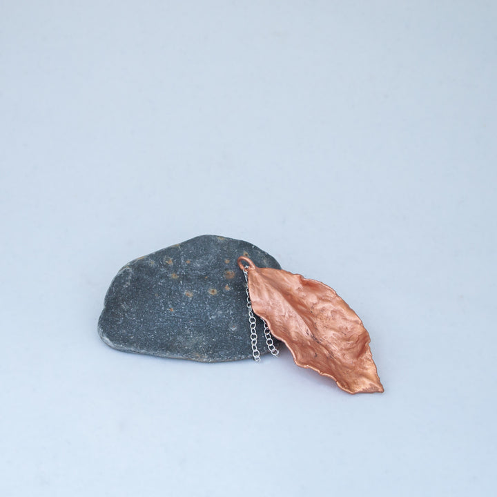 Waving copper leaf, lent on slate coloured stone