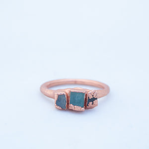 Front on shot of ring laid flat, showing three pieces of aqua-blue shattered window glass, set in copper on ring
