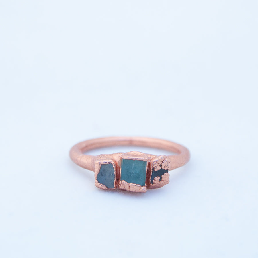 Front on shot of ring laid flat, showing three pieces of aqua-blue shattered window glass, set in copper on ring