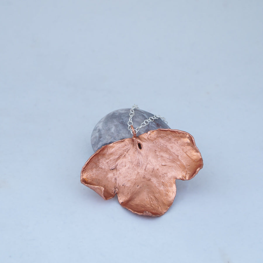 Three segmented leaf in beautiful copper, with silver chain resting on marbled beach stone