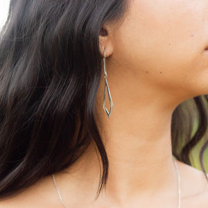 Handmade silver earrings sideways show showing earring dangling from model's ear