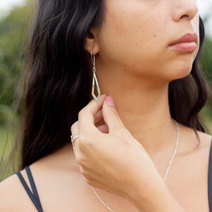 Model's fingers touching handmade silver Dancing Kite earring in her ear