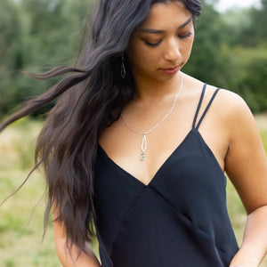 Dancing Kite necklace on model as her hair blows in the cross wind of an open green field