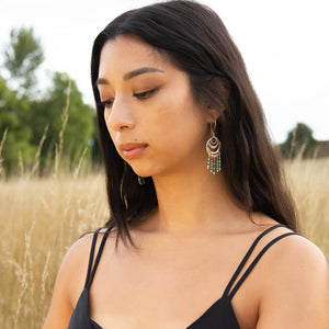 Head and shoulders shot of model in field of grass wearing Spindrift handmade earrings in silver and beads 