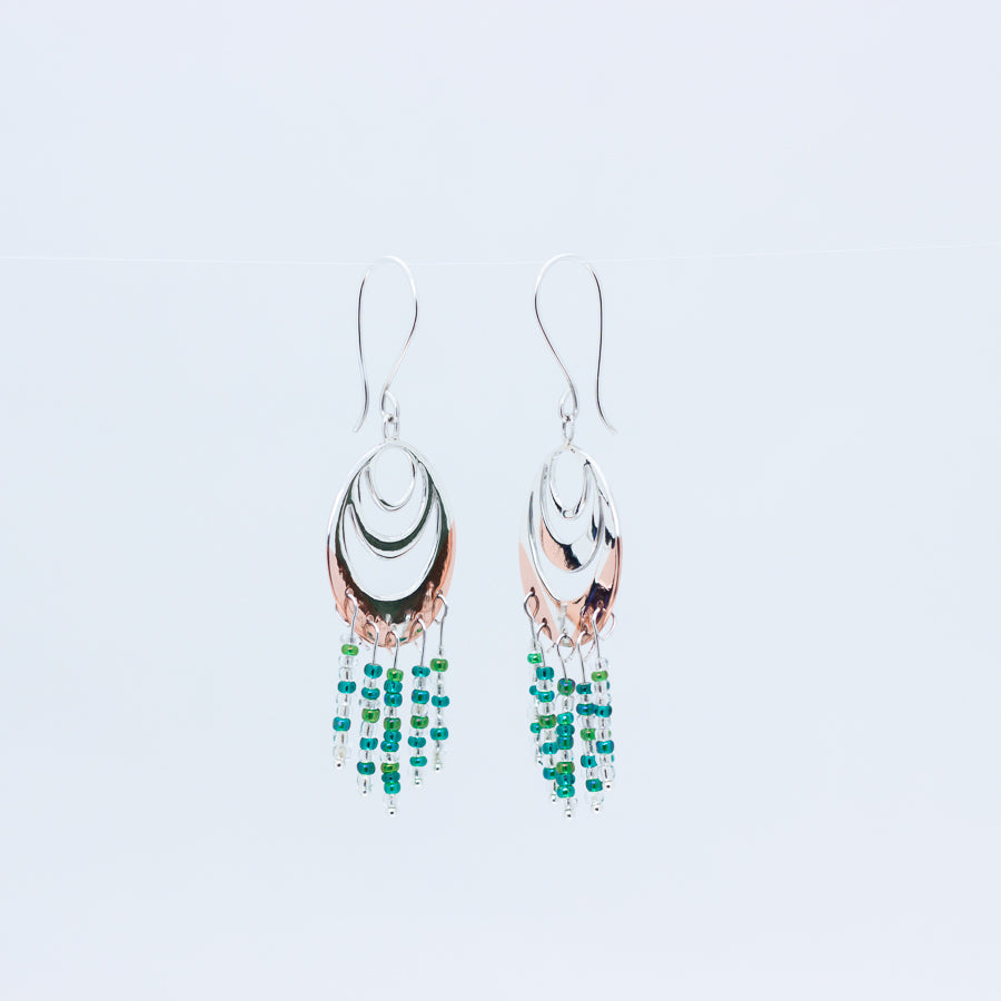 Close up of Spindrift earrings on white background, at angles reflecting each other's swirls