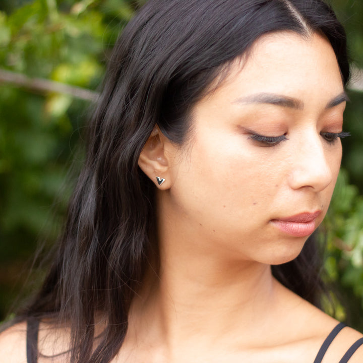 Head and neck shot of Slipstream earrings being worn by model, with trees behind