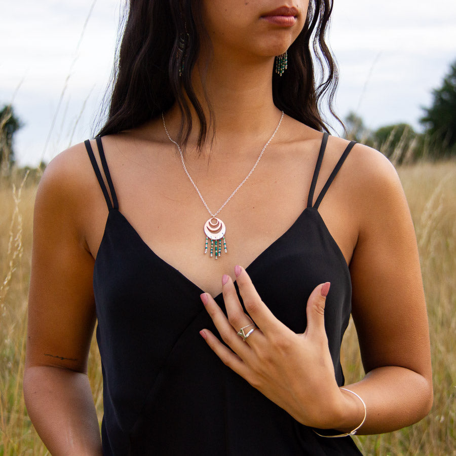 Unusual silver and copper necklace in Spindrift design worn by model in field of long yellow grass