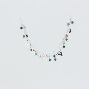 Close up of pretty silver anklet with green and blue beads, on white background