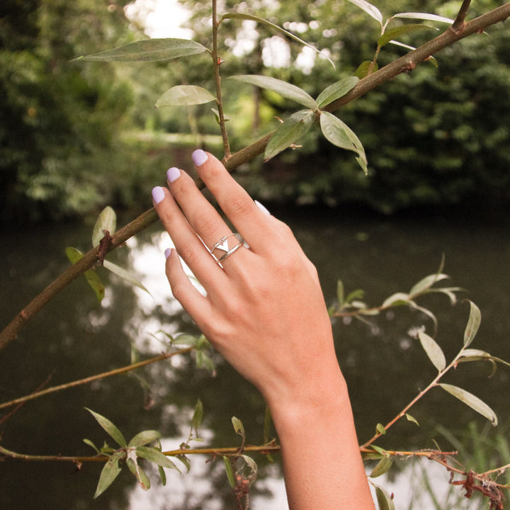 Unique handmade silver ring from the Windblown Collection, Tailwind design, worn by a model holding a branch in front of the river