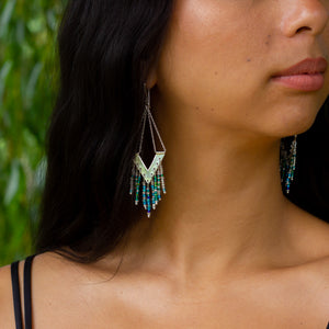 Strikingly unique handmade silver earrings, Windcharm design poke out from behind model's dark hair 