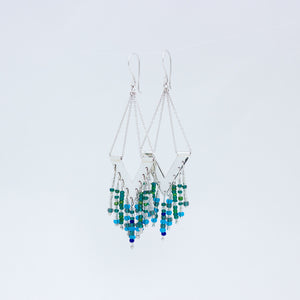 Close up of Windhcharm earrings, displayed close to each other with an overlap on white background