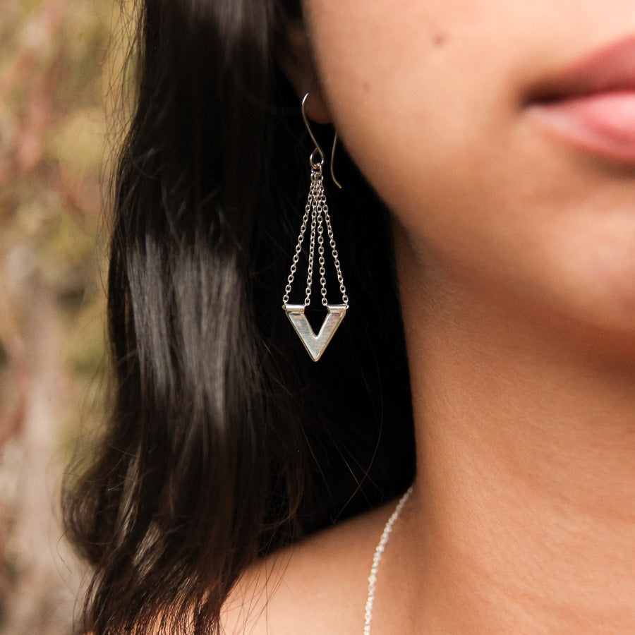 Close up of Zephyr earring worn by model, the silver bright against her dark long hair