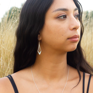 Zephyr earrings from Windblown Collection worn by model looking to right in field of long yellow grass