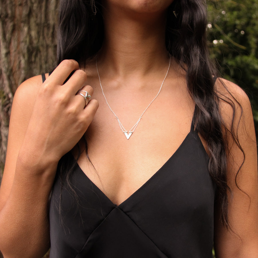 Zephyr necklace on model with her dark wavy hair falling to side and her right hand raised to the other side, Tailwind ring on her finger